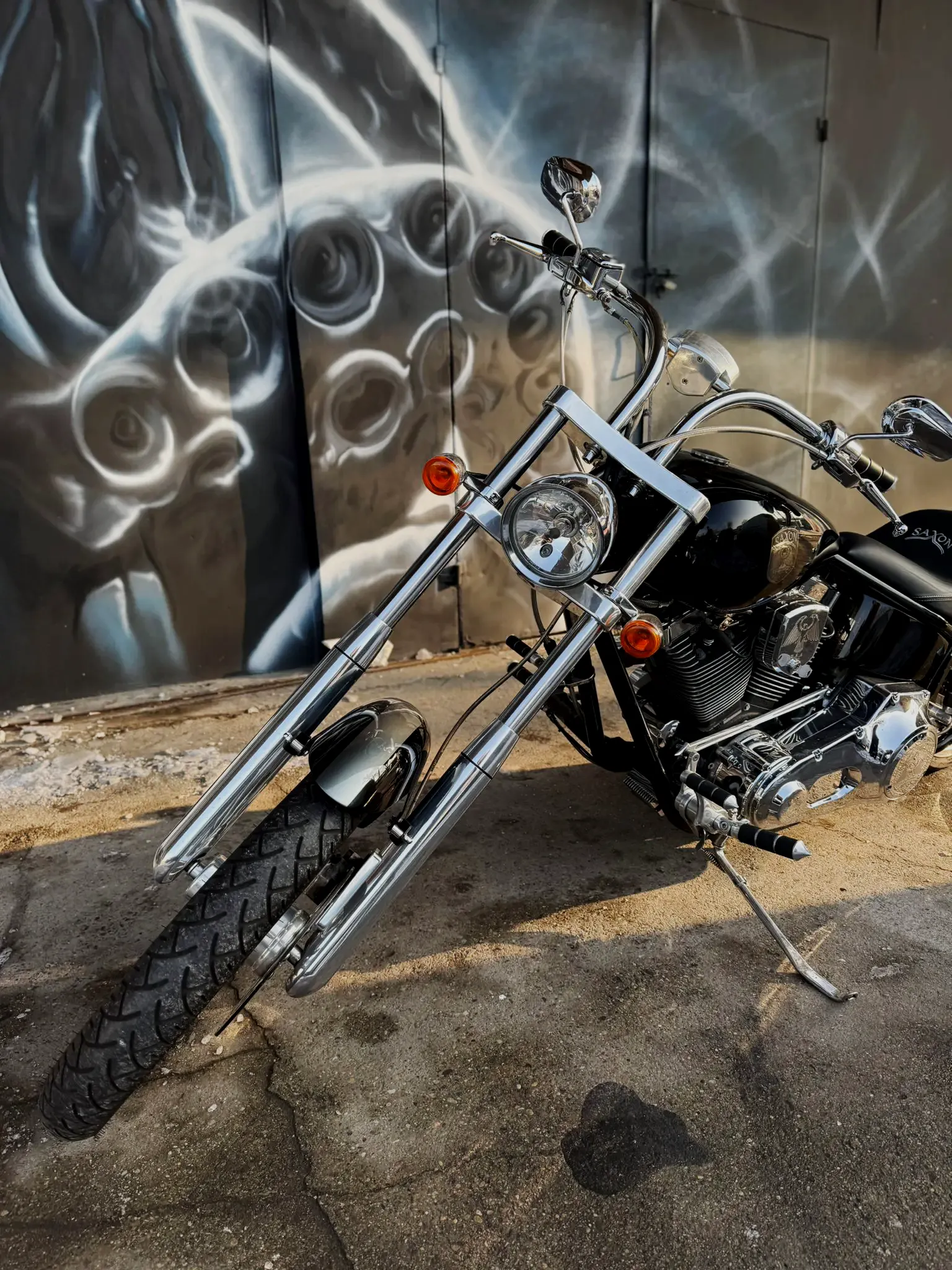 Chopper z chromowanym silnikiem V-twin przed muralem z ośmiornicą w Heavyweight Garage