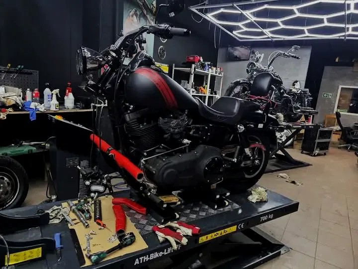Czarny Harley-Davidson z czerwonym pasem na zbiorniku na podnośniku w warsztacie