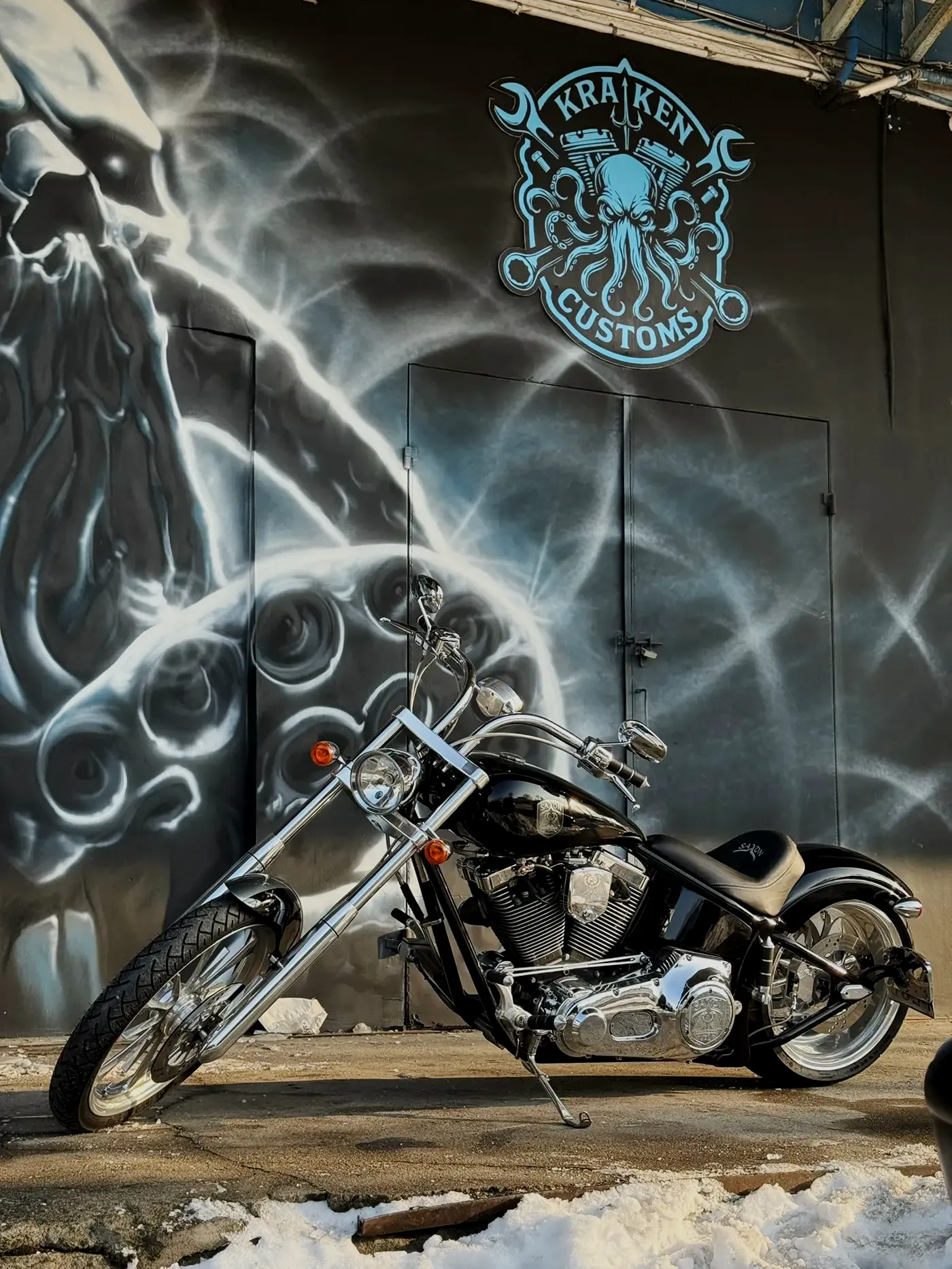 Saxon Firestorm z długim chromowanym widelcem przed muralem z logo Heavyweight Garage